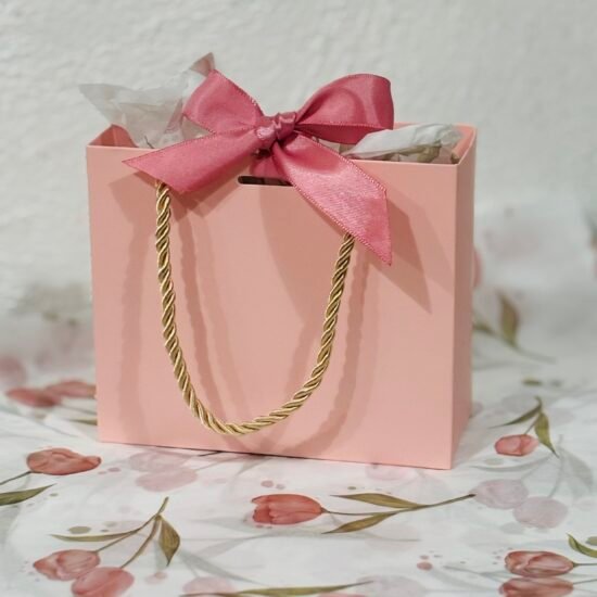 Pink bag with pink ribbon set on tissue paper with pink tulips